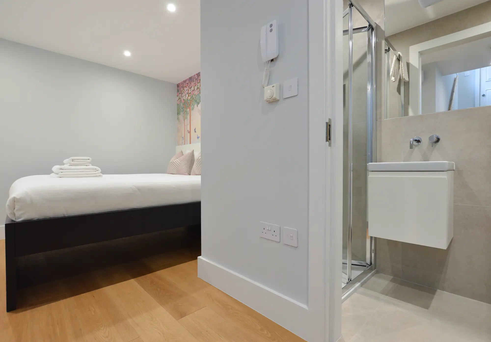 A comfortable double bed and private bathroom with a shower in a basement studio apartment on Portobello Road, Notting Hill