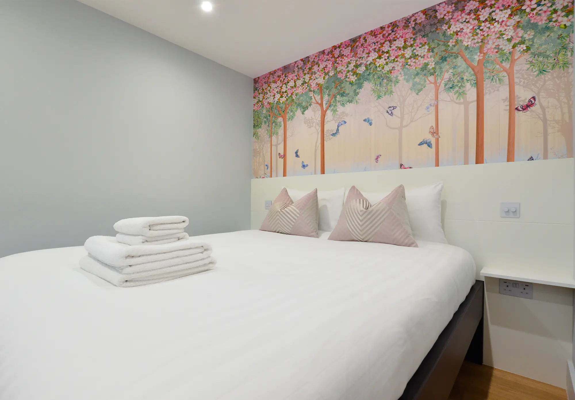 A comfortable double bed with fresh, clean towels in a modernly designed basement studio apartment on Chepstow Villas, Notting Hil