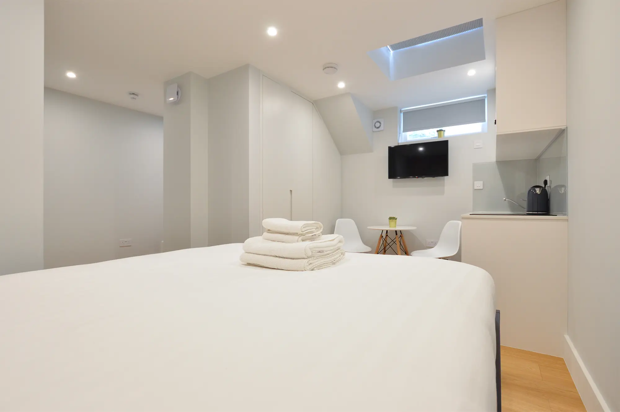 Modern serviced apartment with a double bed, cozy dining area, and skylight window in Notting Hill near Portobello Road