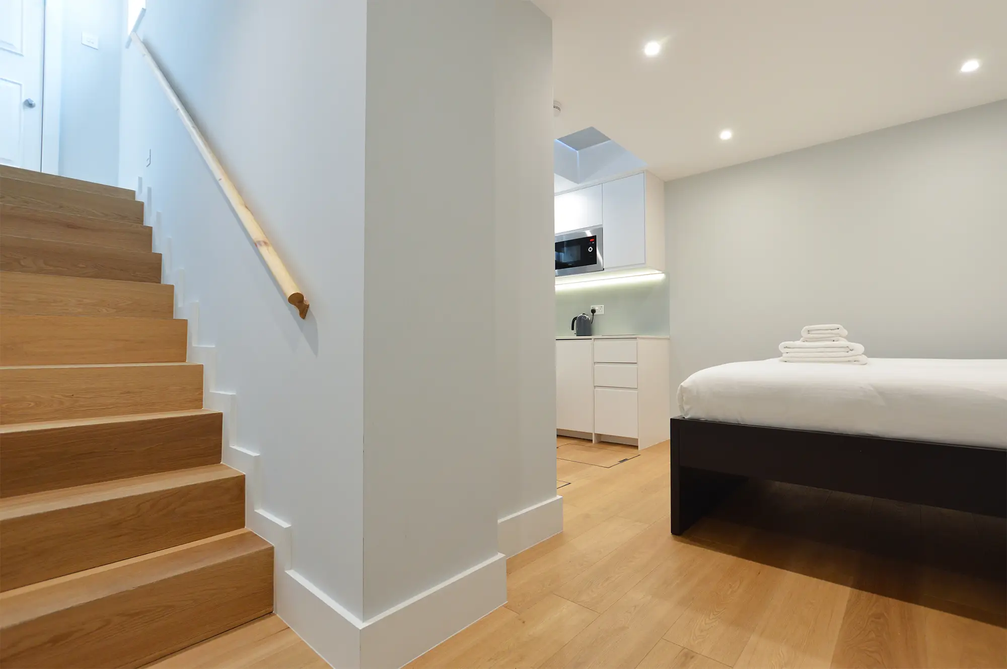 A staircase leading to a modern basement studio with a plush double bed and fully equipped kitchen at 37 Chepstow Villas, Notting Hill