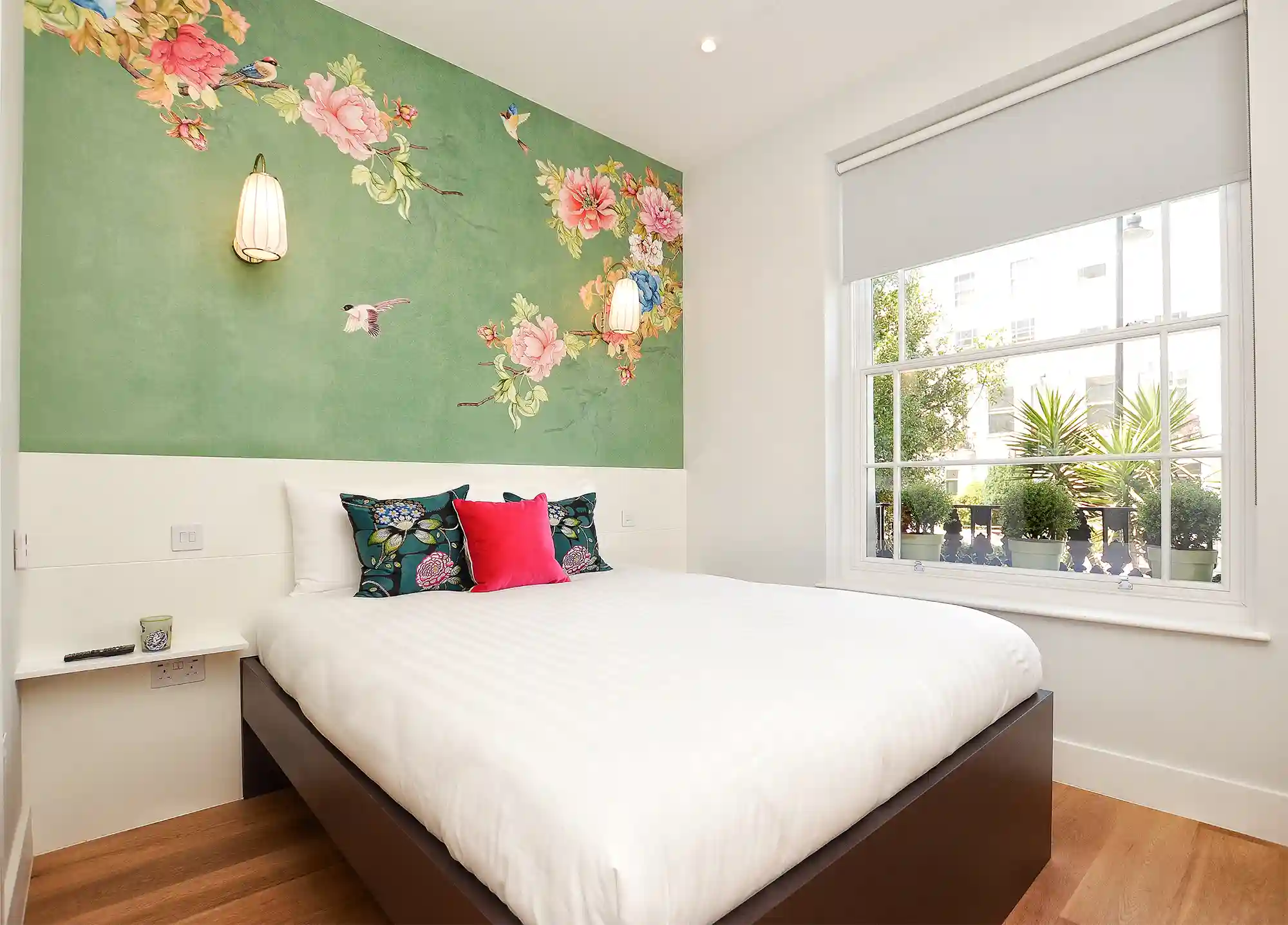 A bright studio apartment in Notting Hill with a comfortable double bed, wooden floors, and large windows offering stunning views of Portobello Market