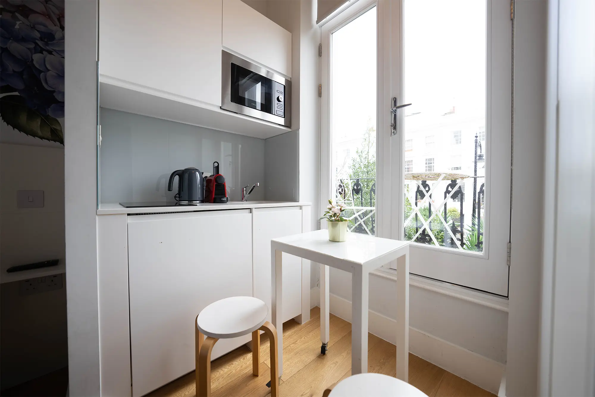 A stylish Notting Hill studio apartment with a fully equipped kitchenette, a cozy dining area, and a balcony overlooking Portobello Road