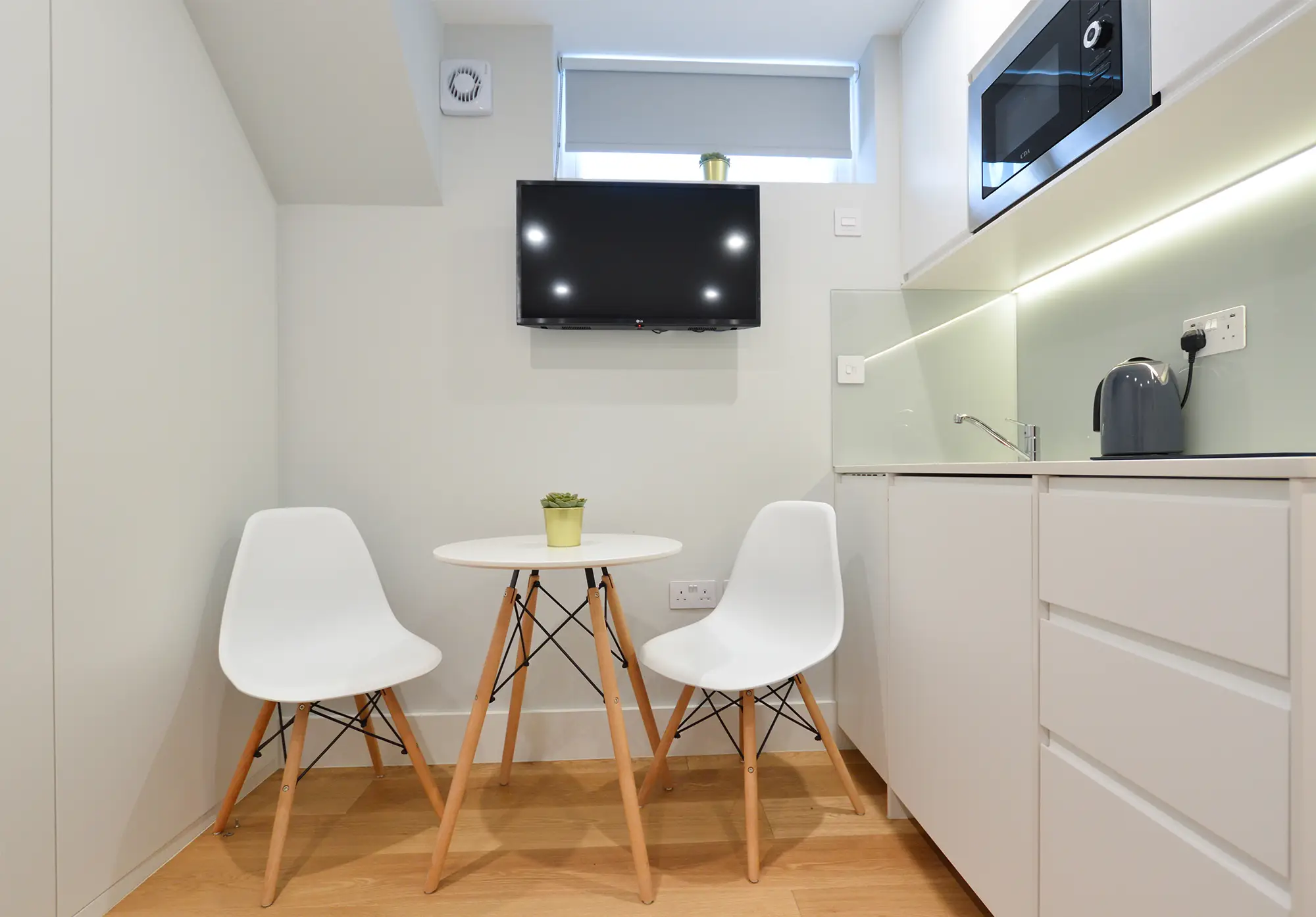 Modern serviced studio apartment in Notting Hill with an elegant, fully equipped kitchen, a smart TV unit, and a dining area