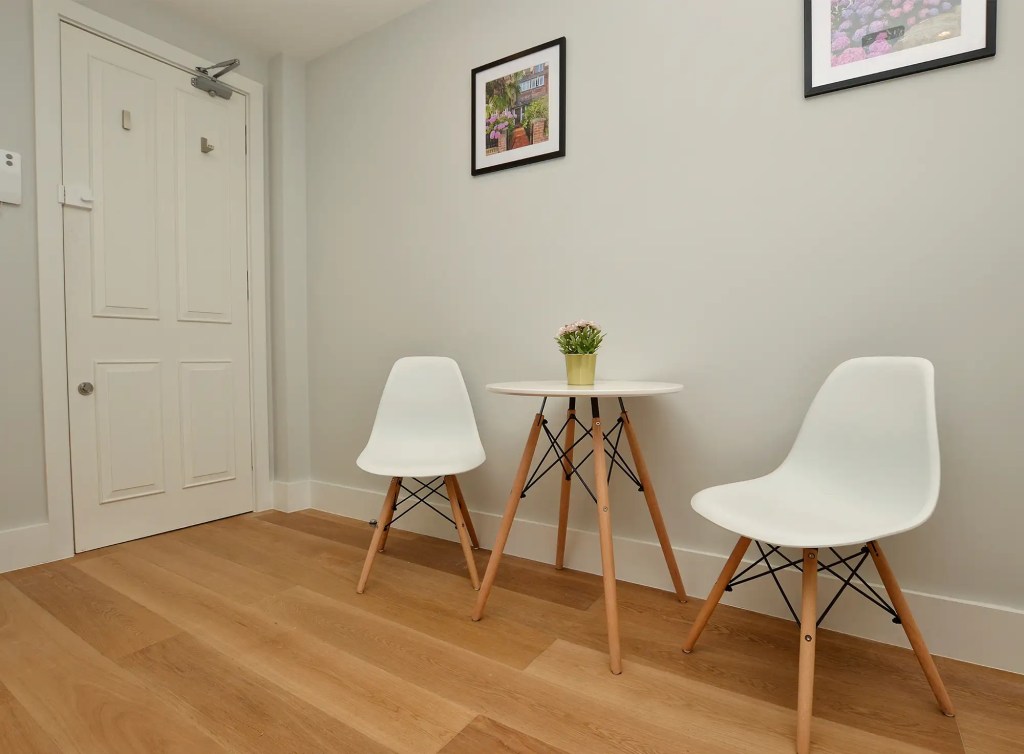 An airy and spacious studio apartment in Notting Hill, with wooden floors, a modern kitchenette, a dining area, and access to a cozy private yard.