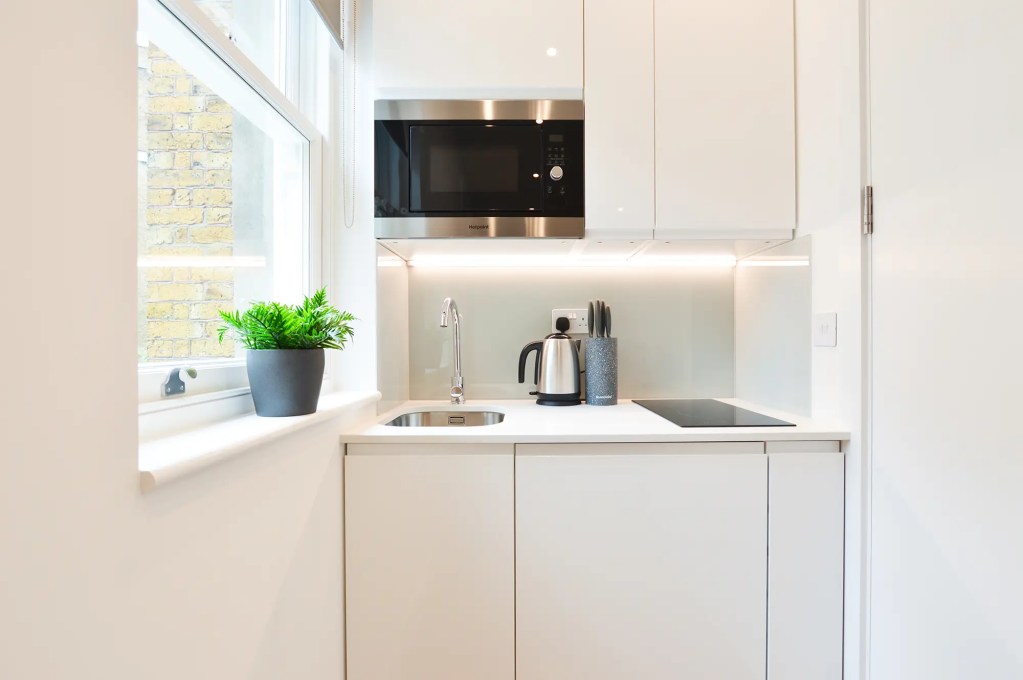 A comfortable double bed and light-filled window in a small one-bedroom apartment in Marylebone at 162 New Cavendish, London