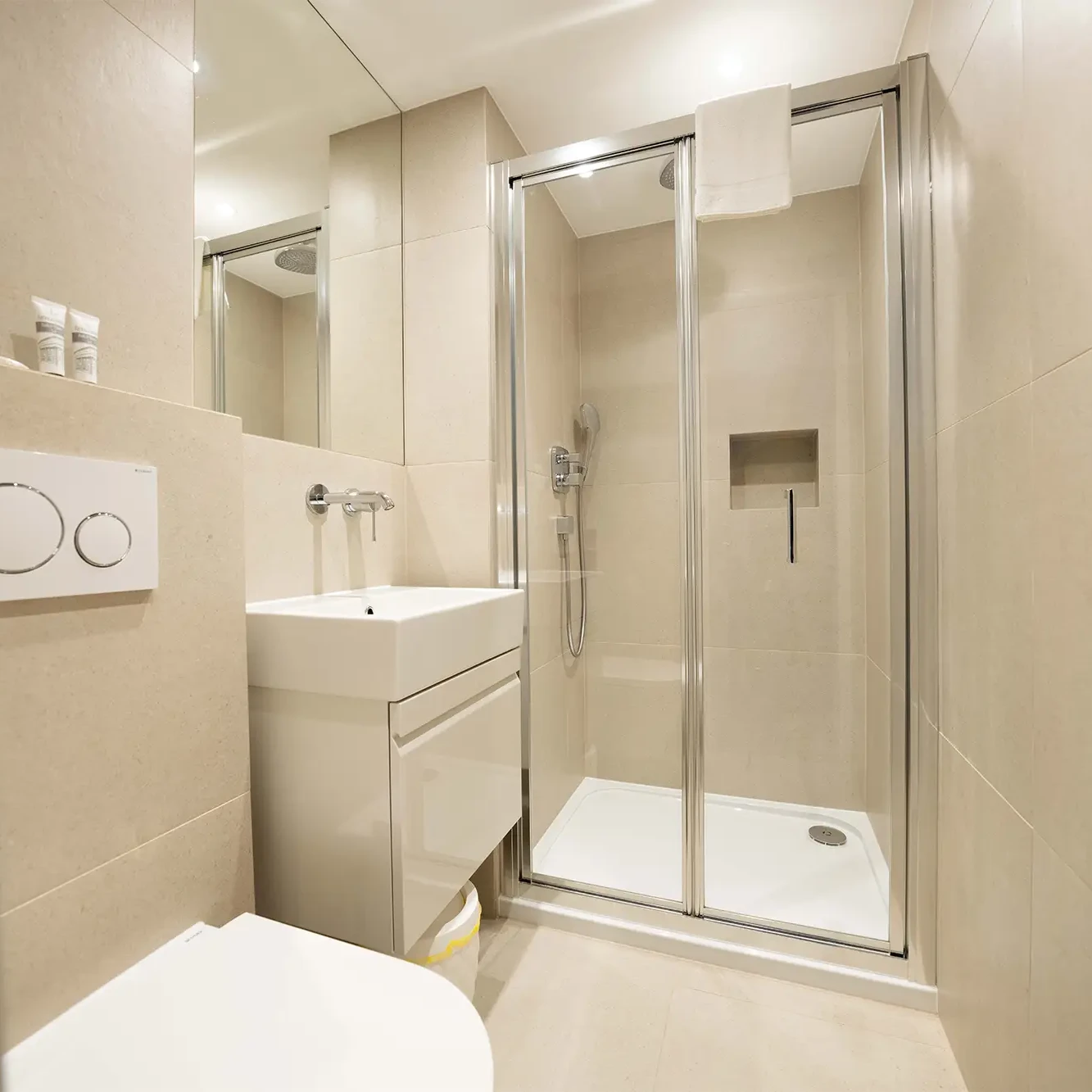 A stylish private bathroom with a shower, heated towel rail, and underfloor heating in a luxury serviced apartment in central London