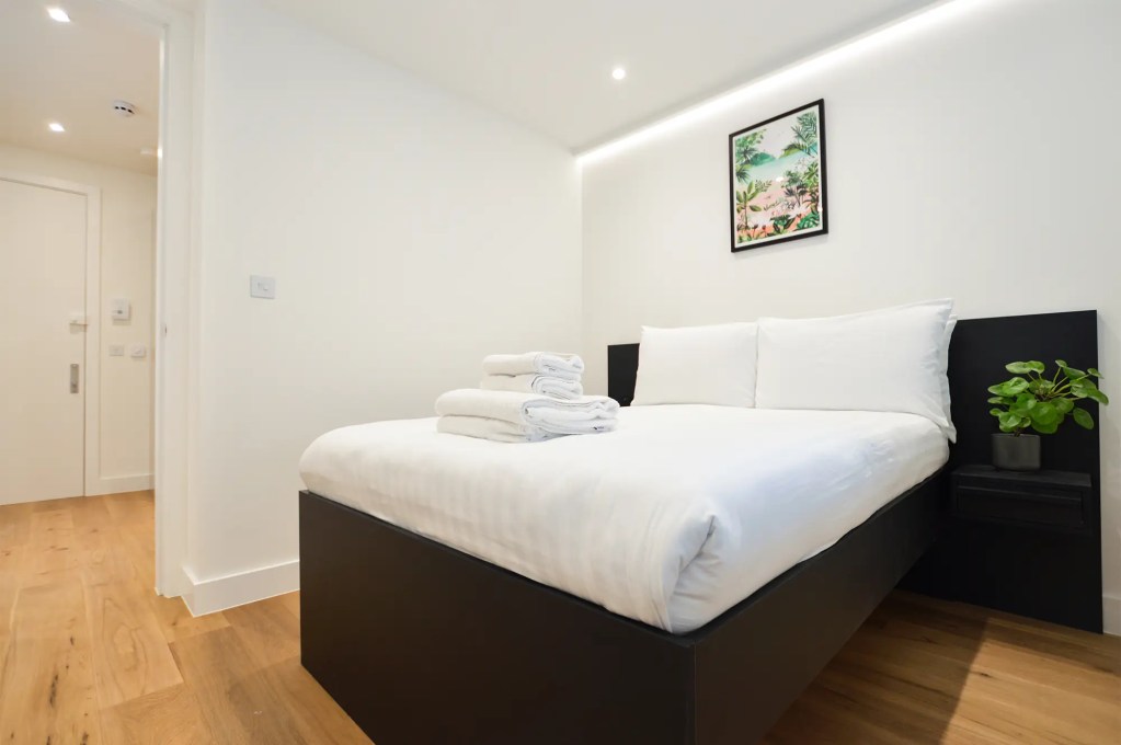 A comfortable double bed and light-filled window in a small one-bedroom apartment in Marylebone at 162 New Cavendish, London