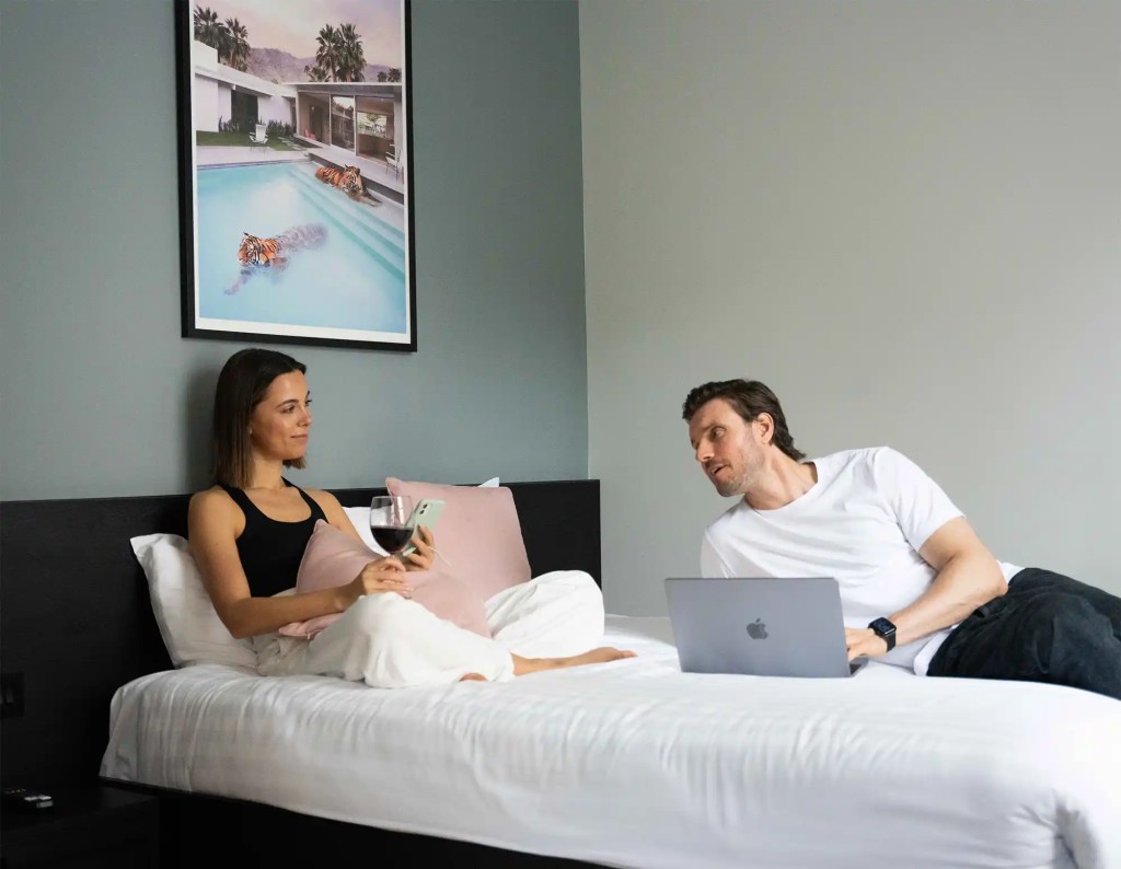 A young couple resting on a luxurious double bed in a modern serviced apartment in Marylebone, London