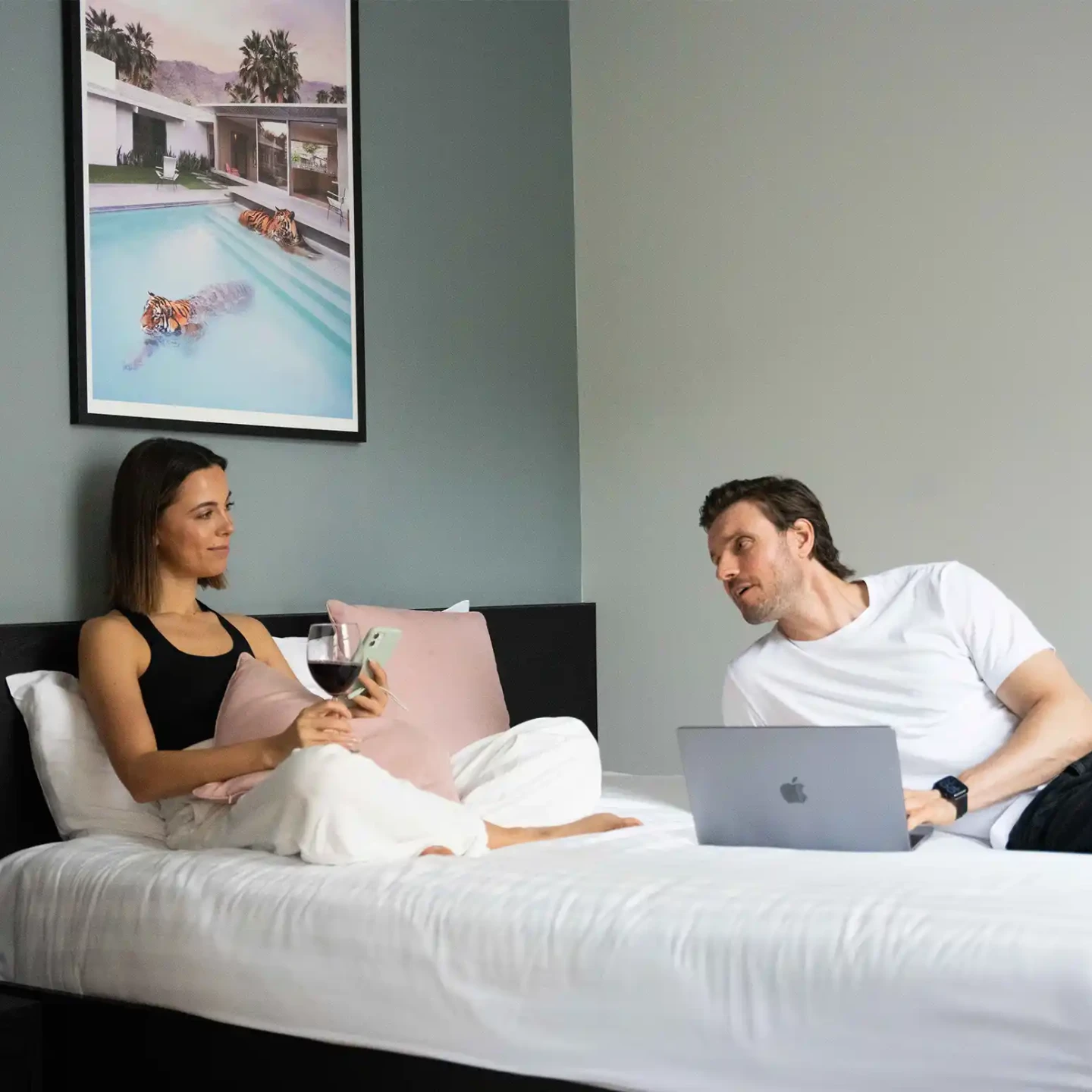 A young couple resting on a luxurious double bed in a modern serviced apartment in Marylebone, London