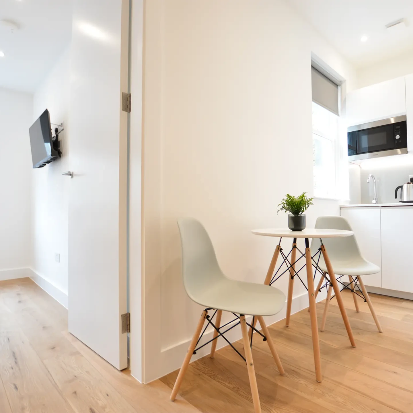 A comfortable living area with a dining table and a fully equipped kitchenette near a cozy bedroom with a double bed in a small one-bedroom apartment in Marylebone at 162 New Cavendish, London
