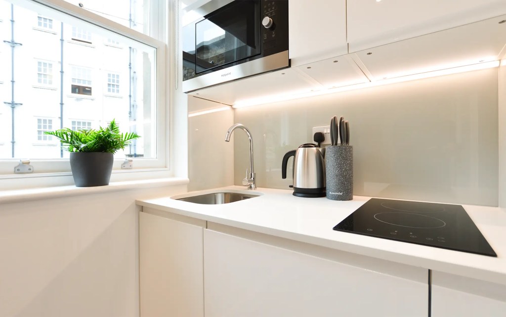 A comfortable double bed and light-filled window in a small one-bedroom apartment in Marylebone at 162 New Cavendish, London