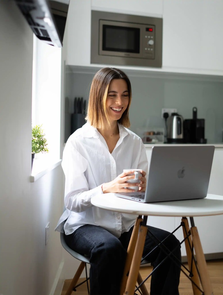 A young professional working on her computer in the dining area of a stylish studio apartment at 162 New Cavendish St, Marylebone, Central London.