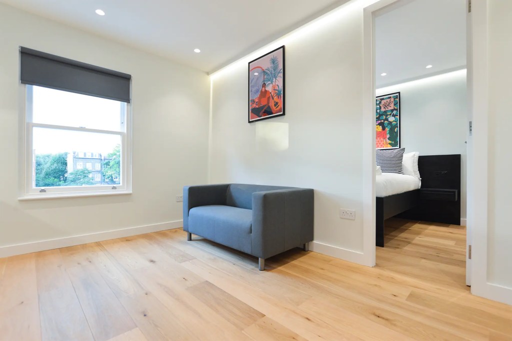 Spacious one-bedroom apartment at Earls Court serviced studios with a stylish living area, featuring a sofa and a window with natural light