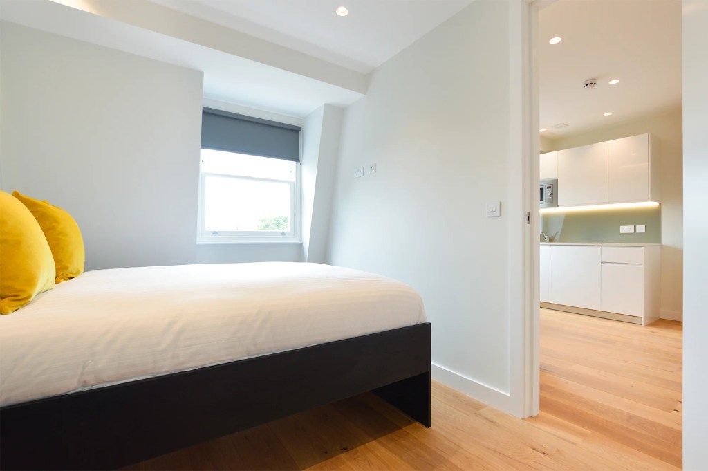 A comfortable bedroom with a double bed and a spacious living area in a one-bedroom apartment located in Earl's Court