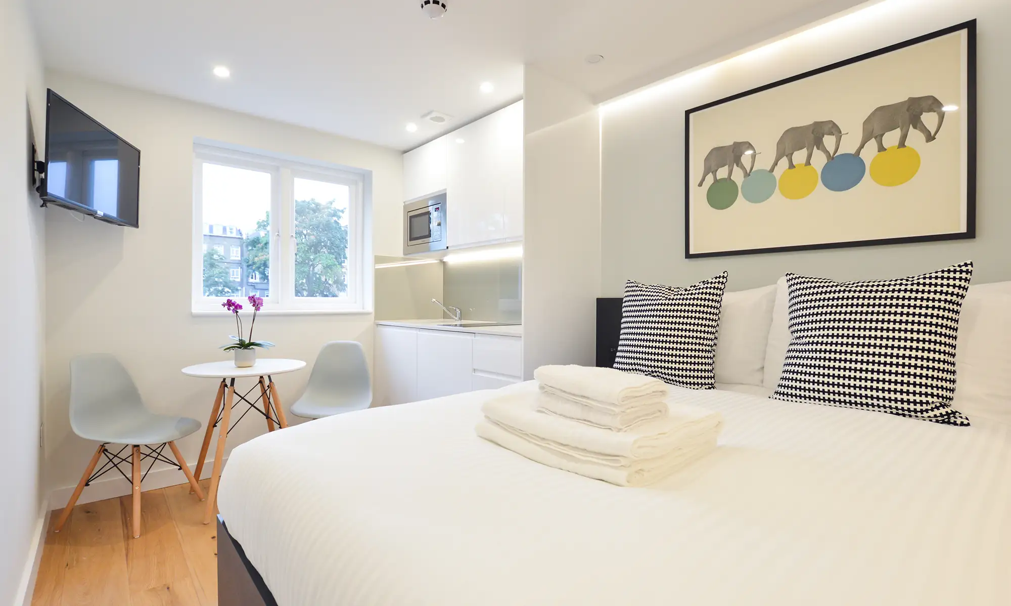 Comfortable double bed next to a stylish, fully equipped kitchenette in boutique apartments near West Brompton in Earl's Court, London.