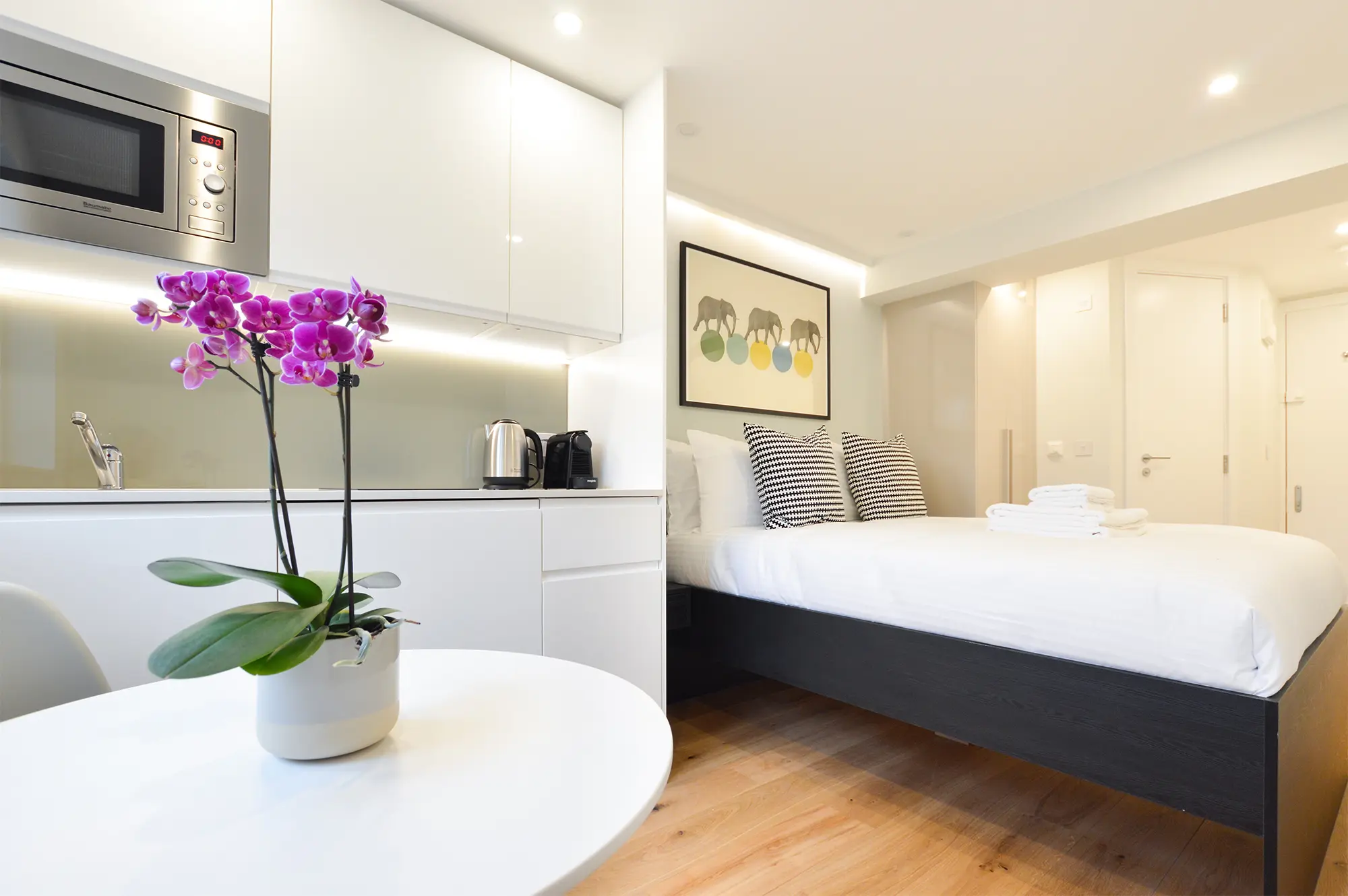 Comfortable double bed next to a stylish, fully equipped kitchenette in an Earl's Court serviced apartment in London. Stayprime studios in London combine modern elegance and practicality at affordable rates