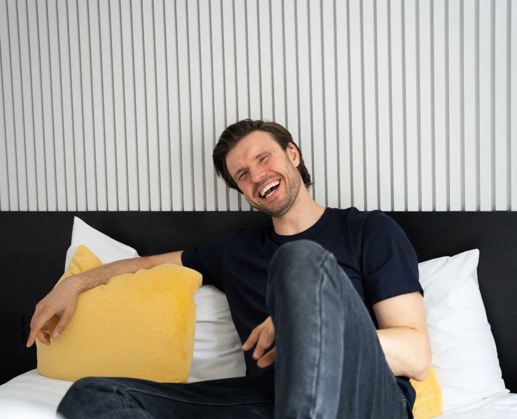 A young professional unwinds on a cozy double bed in a StayPrime serviced apartment in Fitzrovia