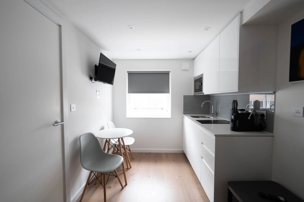 Elegant, fully equipped kitchen area with dining table and chairs for a comfortable stay in a Fitzrovia one-bedroom apartment