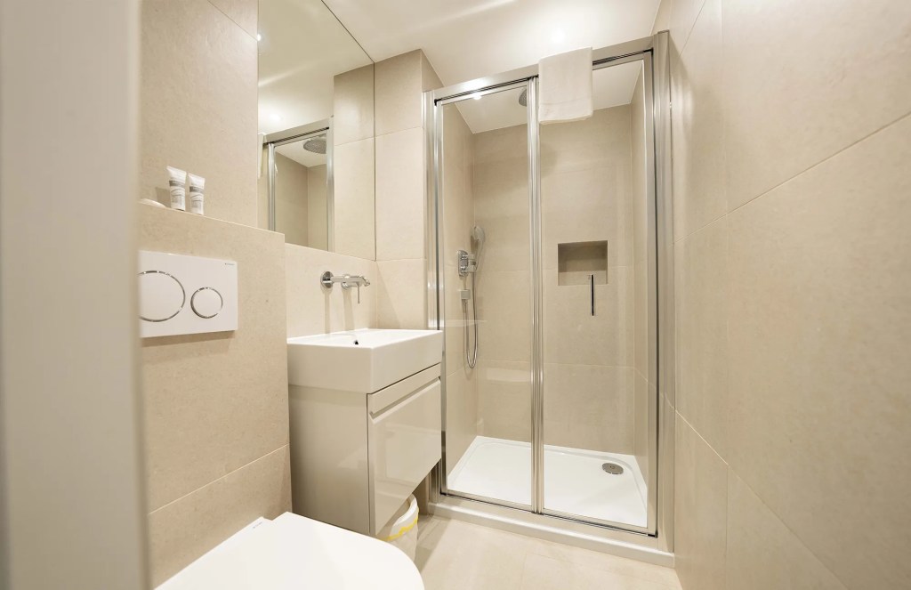 Luxurious private bathroom with shower, toilet, warm towels, and complimentary toiletries in StayPrime serviced apartments, offering an indulgent and comfortable experience for a luxury stay in London