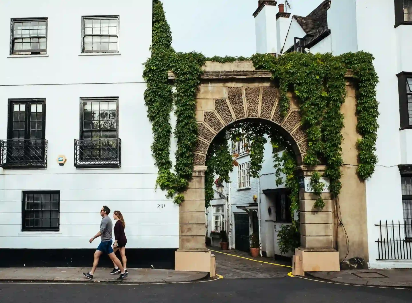 A young couple strolls along a beautiful street in Kensington area, London, admiring the unique architecture near the Kensington Serviced Apartments