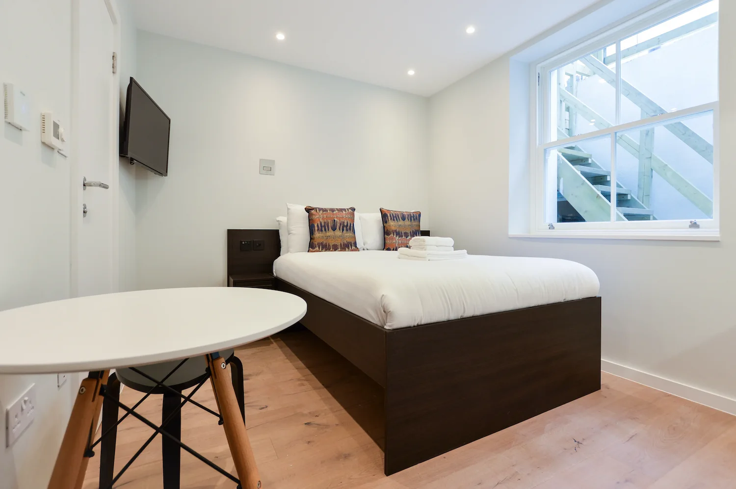 Affordable serviced apartment in Fitzrovia, Central London with double bed, TV unit, dining area, and light-filled window