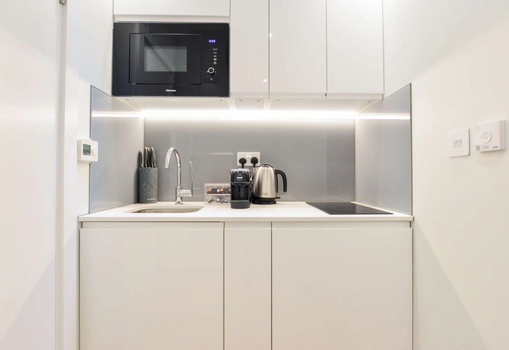 Comfortable double bed near dining area with table and chairs, and fully equipped kitchenette in a serviced apartment in Fitzrovia