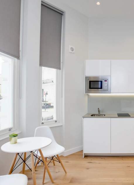 A bright long term let apartment in central London with high ceilings, wooden flooring, a fully equipped kitchenette, and a cozy bed
