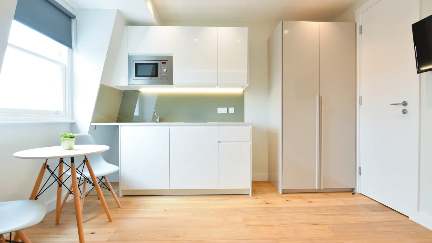 A modern serviced apartment in Earls Court with a fully equipped kitchen, dining area, wooden floors, and spacious windows