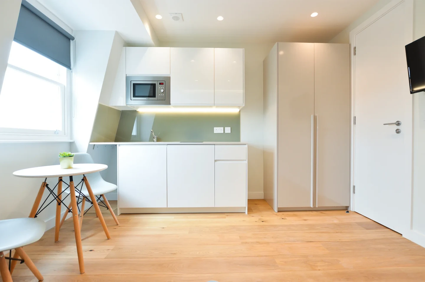 A modern serviced apartment in Earls Court with a fully equipped kitchen, dining area, wooden floors, and spacious windows