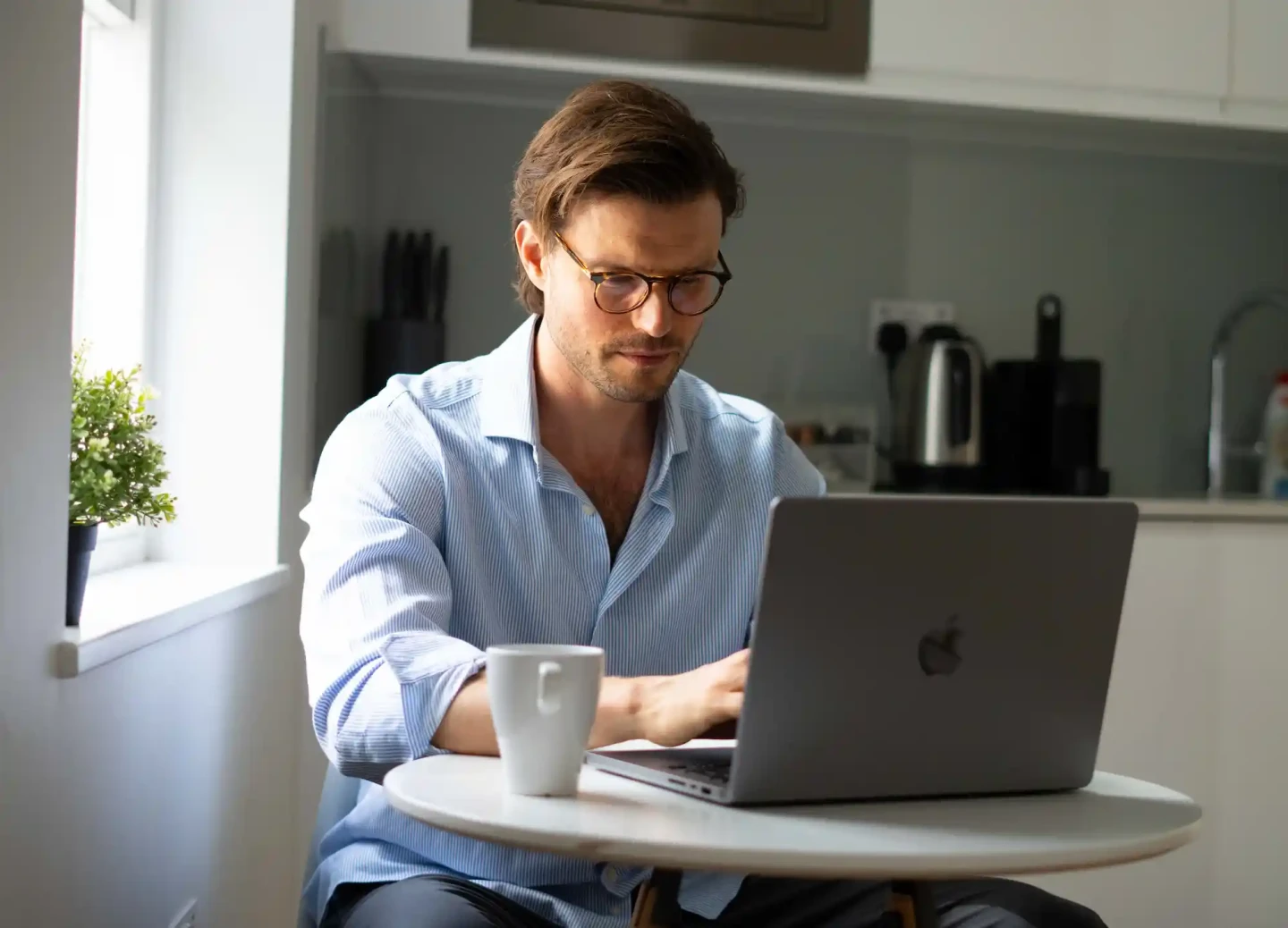 A young professional working on his laptop at a comfortable desk in a serviced apartment in Central London.