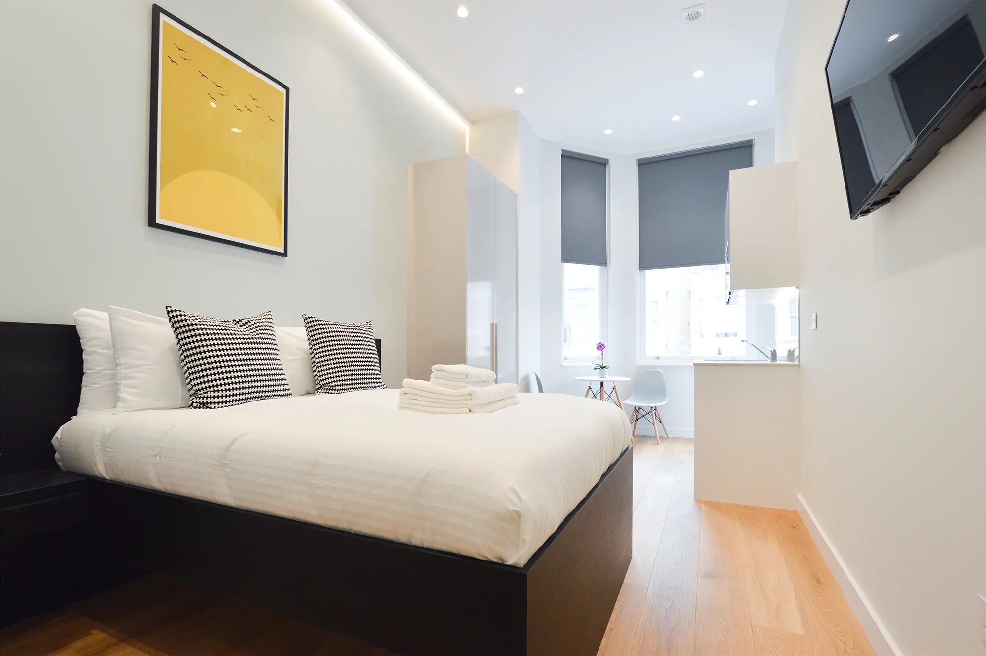Modern studio apartment with wooden floors, fully equipped kitchen, and comfortable double bed at Stayprime Serviced Apartments in central London