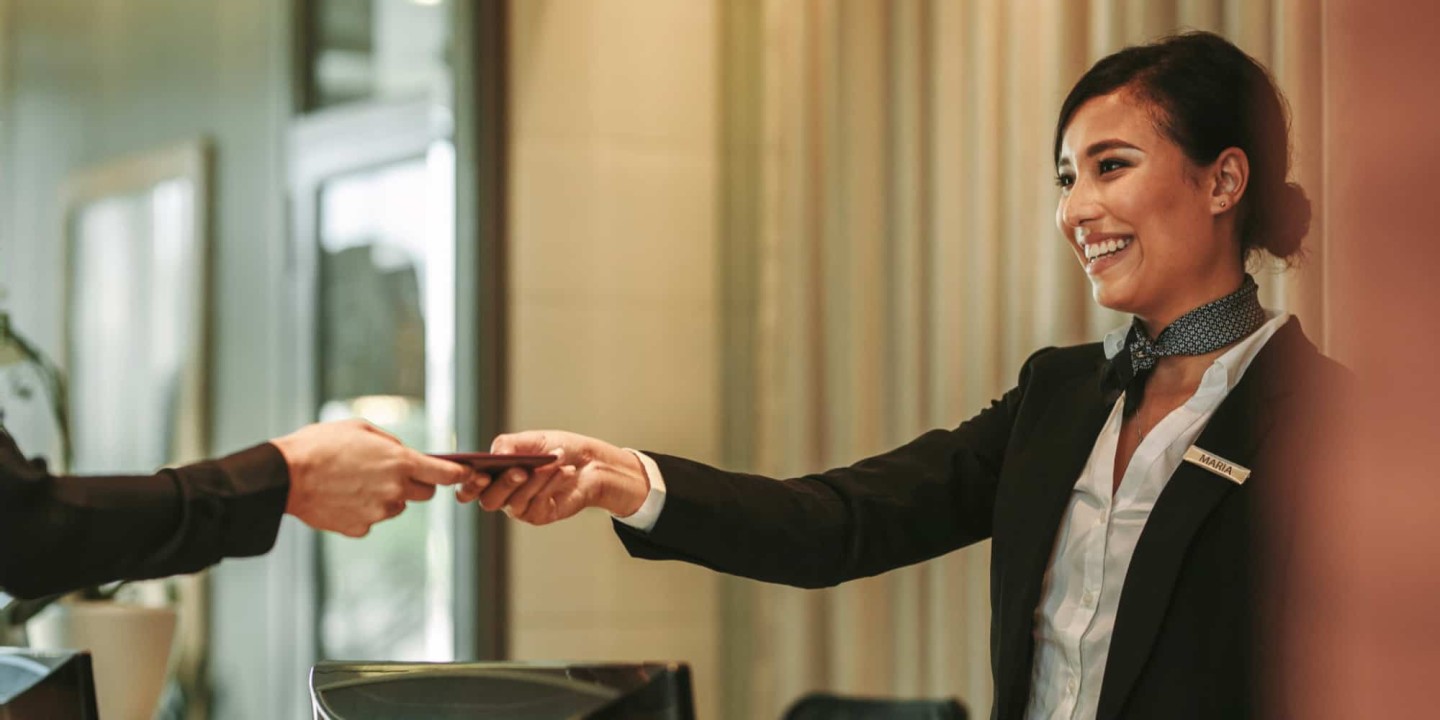 A receptionist at a London aparthotel kindly checking in guests at the front desk